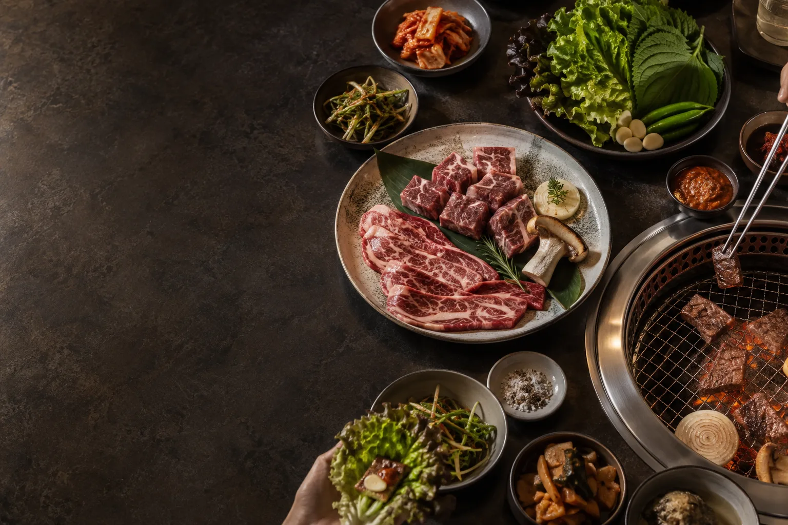 한국식 상차림에 생고기, 숯불구이, 쌈 채소와 반찬을 함께 놓은 이미지